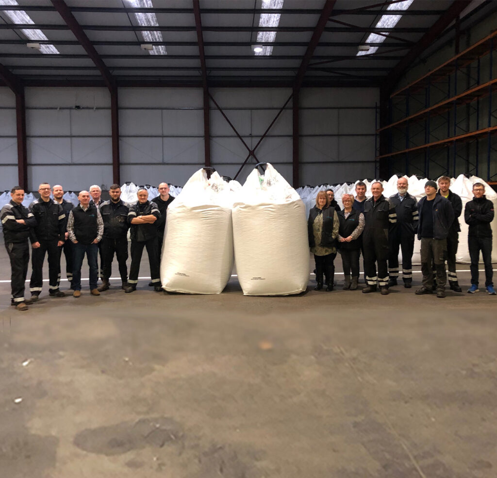 Staff at Cooke's Invergordon feed mill with two large feed bags