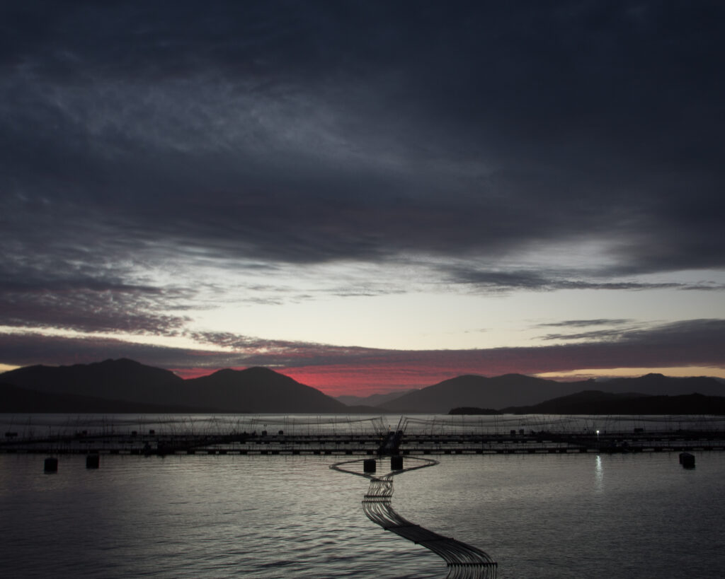 Fish farm in the sea, with mountains and dark clouds in the background